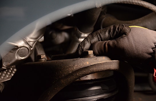 Mechanic finger tightening the upper nuts on the strut assembly